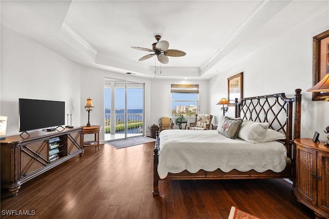 bedroom with dark wood-type flooring, ceiling fan, access to exterior, ornamental molding, and a tray ceiling