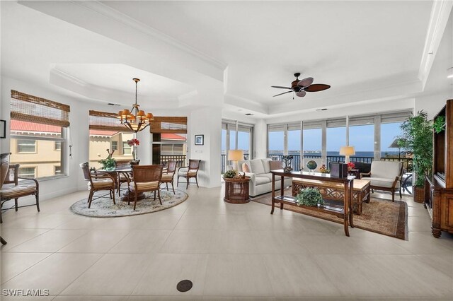 living room featuring ceiling fan with notable chandelier, light tile patterned floors, and a tray ceiling