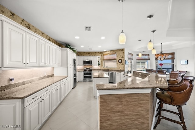 kitchen with kitchen peninsula, white cabinets, pendant lighting, and appliances with stainless steel finishes