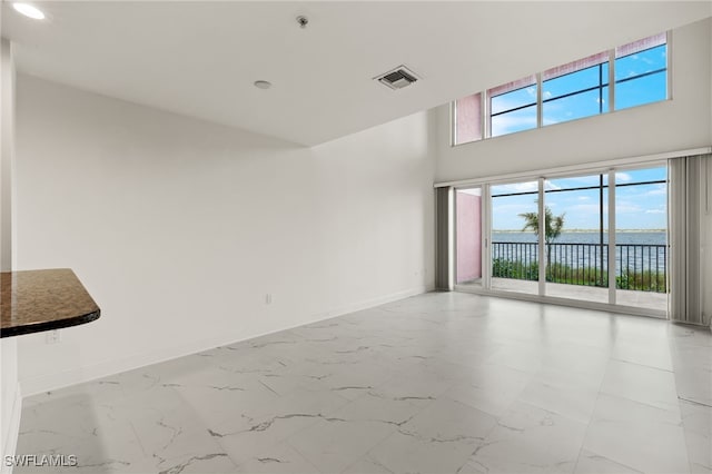 spare room with a wealth of natural light, a high ceiling, and a water view