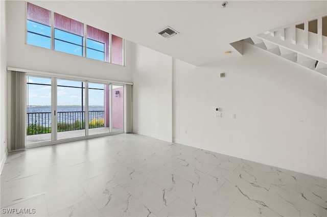 empty room featuring a water view and a towering ceiling