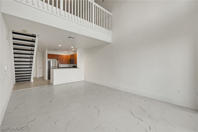 unfurnished living room with a towering ceiling