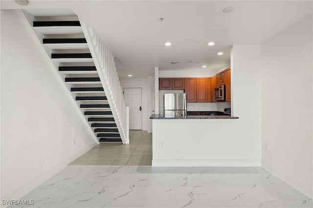 kitchen featuring stainless steel appliances, dark stone counters, and kitchen peninsula