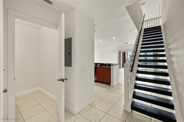 stairs with sink, tile patterned floors, and electric panel