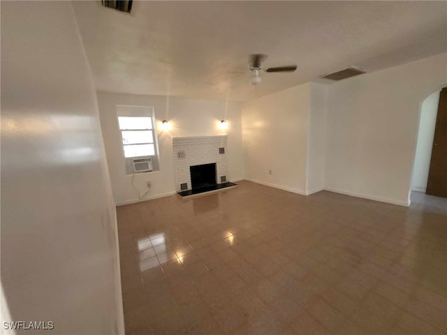 unfurnished living room with a brick fireplace, cooling unit, tile patterned floors, and ceiling fan