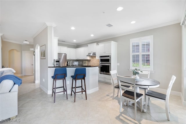 kitchen with appliances with stainless steel finishes, tasteful backsplash, crown molding, sink, and white cabinets