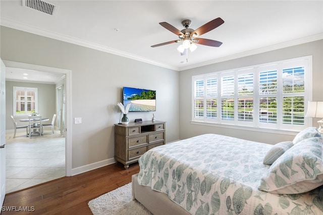 bedroom featuring multiple windows, ceiling fan, dark hardwood / wood-style flooring, and ornamental molding