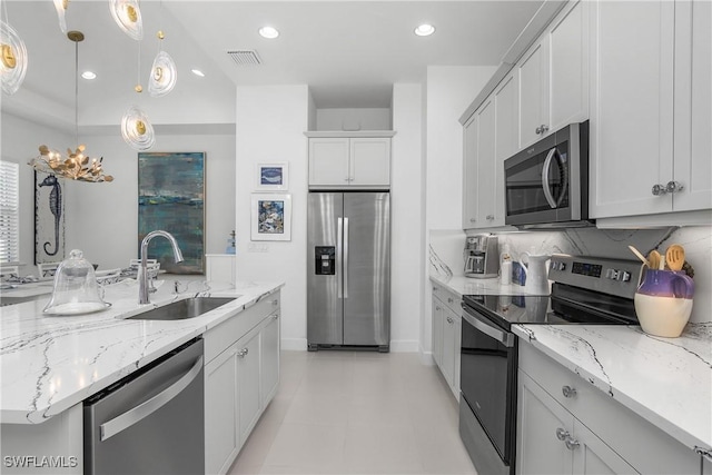 kitchen featuring sink, hanging light fixtures, appliances with stainless steel finishes, tasteful backsplash, and white cabinetry