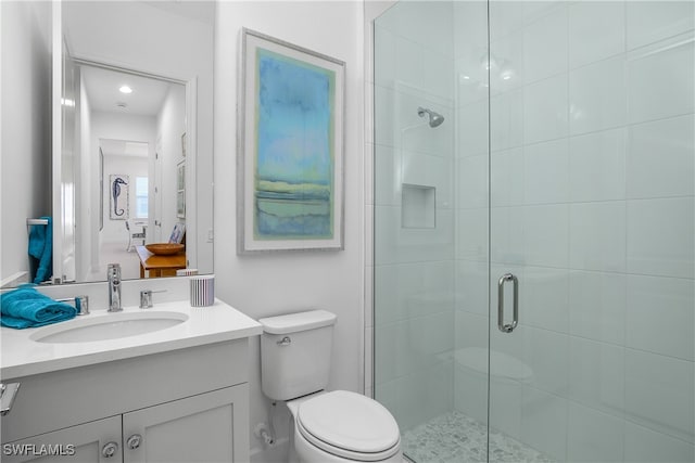 bathroom with vanity, toilet, and a shower with door