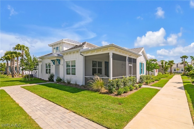 view of side of home with a sunroom and a yard