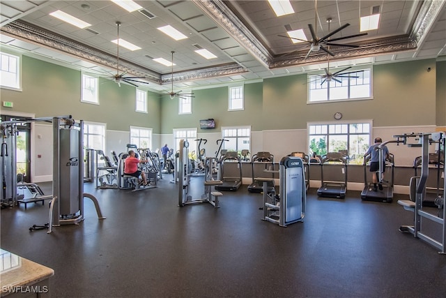 gym featuring ceiling fan, a drop ceiling, crown molding, and a high ceiling