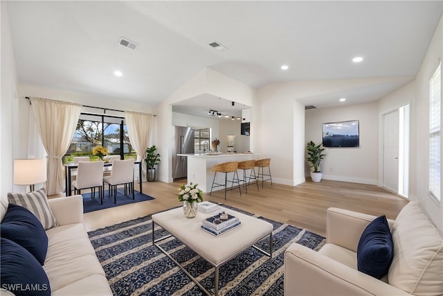 living room featuring light hardwood / wood-style floors and vaulted ceiling