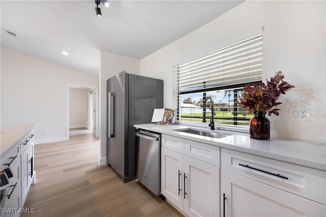 kitchen featuring light hardwood / wood-style flooring, sink, light stone countertops, white cabinets, and appliances with stainless steel finishes