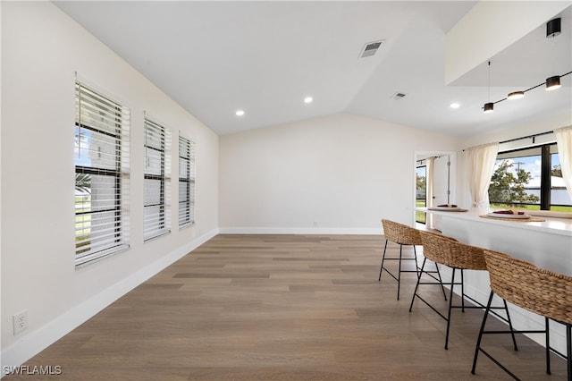 interior space featuring light wood-type flooring, lofted ceiling, and a kitchen breakfast bar