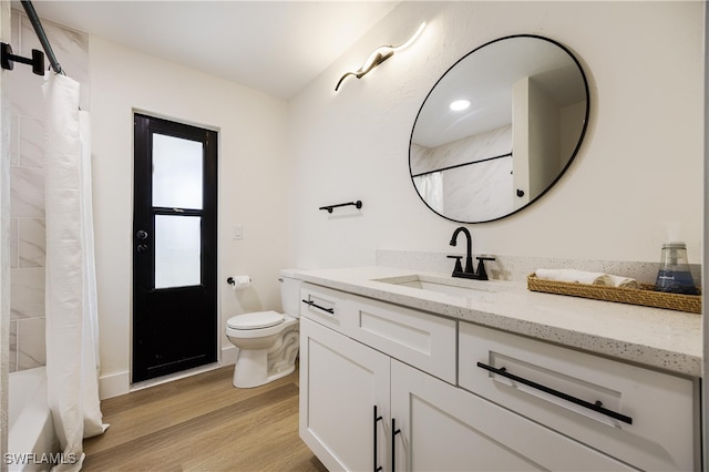 full bathroom with vanity, hardwood / wood-style flooring, shower / bath combo with shower curtain, and toilet