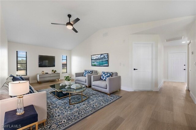 living room featuring ceiling fan, light wood-type flooring, and vaulted ceiling