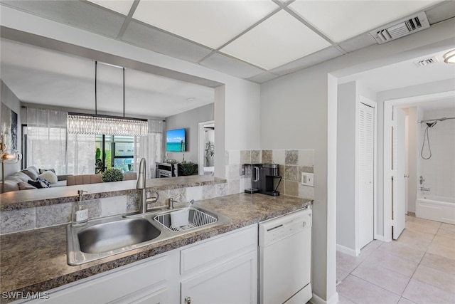 kitchen with a drop ceiling, sink, white dishwasher, white cabinets, and light tile patterned floors