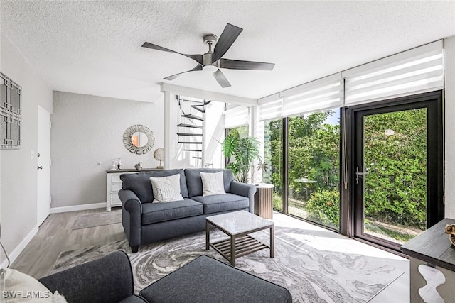 living room with a textured ceiling, light wood-type flooring, and ceiling fan