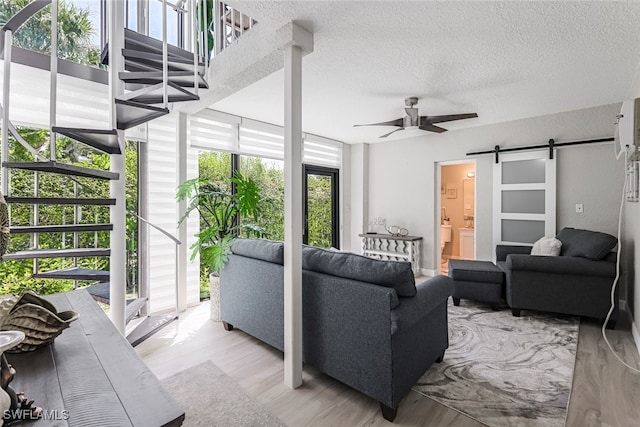 807 River Point Dr Unit 102D, Naples, FL 34102 - living room featuring a barn door, wood finished floors, a ceiling fan, and a textured ceiling