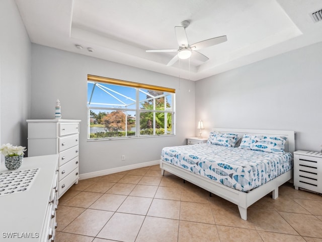 tiled bedroom featuring ceiling fan and a tray ceiling