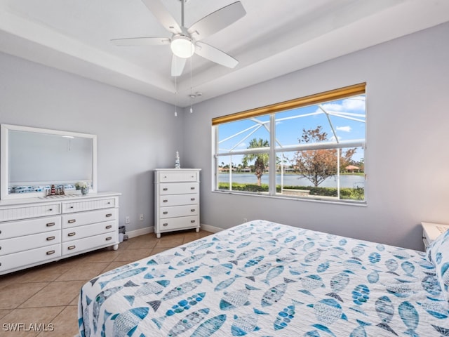 tiled bedroom featuring ceiling fan and a tray ceiling