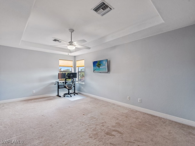 spare room featuring ceiling fan, light colored carpet, and a tray ceiling