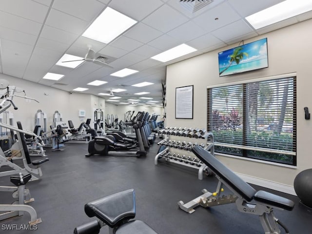 exercise room with a paneled ceiling and a healthy amount of sunlight