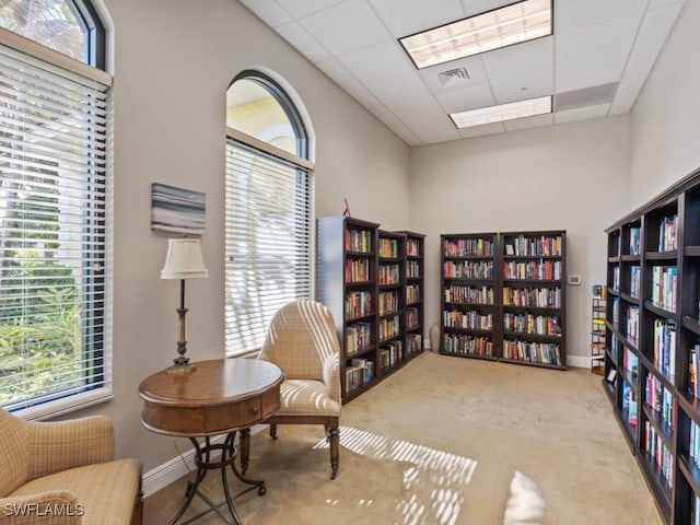 sitting room with a paneled ceiling and light carpet