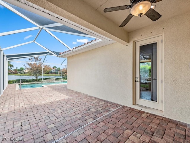 view of patio with a water view, ceiling fan, and a lanai