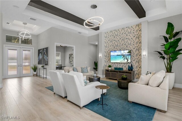 living room with light wood-type flooring, french doors, and a tray ceiling