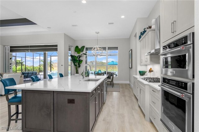 kitchen featuring stainless steel appliances, sink, an inviting chandelier, white cabinets, and light hardwood / wood-style floors