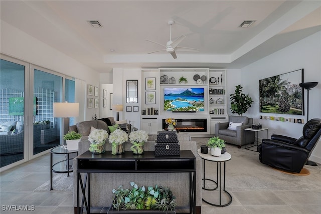 living room featuring light tile patterned flooring, a tray ceiling, and ceiling fan