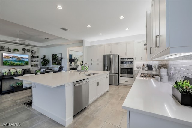 kitchen featuring a kitchen island with sink, sink, a kitchen bar, white cabinetry, and appliances with stainless steel finishes