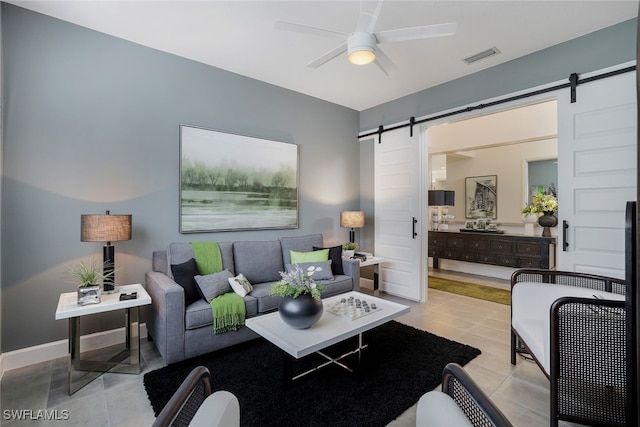 tiled living room with ceiling fan and a barn door