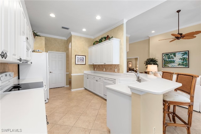 kitchen featuring white appliances, a kitchen breakfast bar, sink, kitchen peninsula, and white cabinetry