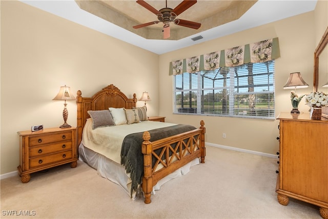 carpeted bedroom with ceiling fan and a raised ceiling