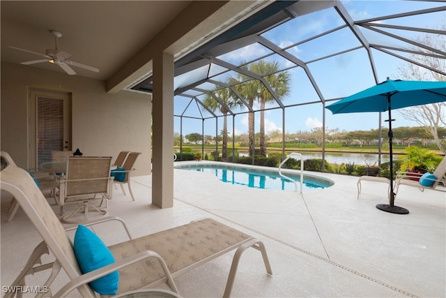 view of pool with a lanai, a water view, ceiling fan, and a patio