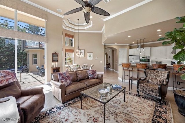 living room featuring light tile patterned floors, arched walkways, a high ceiling, ceiling fan, and crown molding