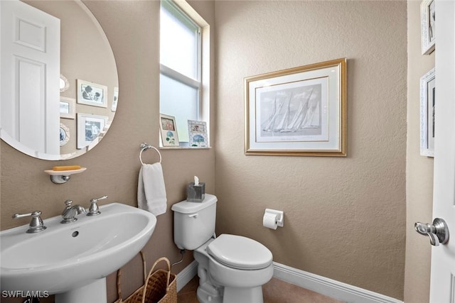 half bathroom featuring a sink, toilet, and baseboards