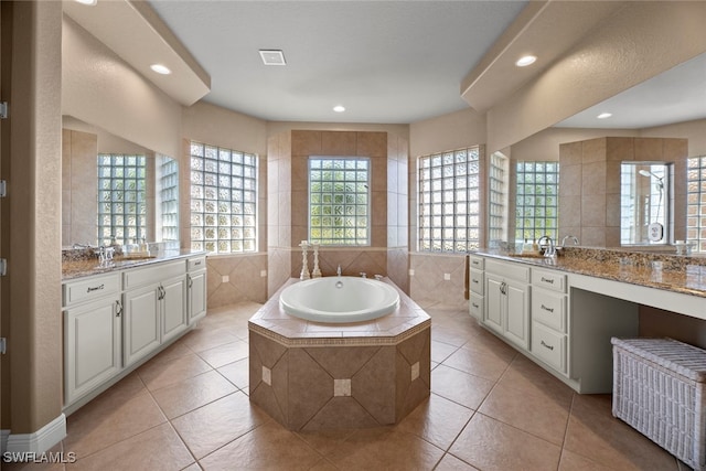 bathroom featuring a relaxing tiled tub, tile patterned flooring, vanity, and tile walls