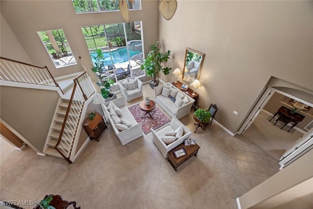 living room featuring tile patterned flooring, a towering ceiling, baseboards, and stairs