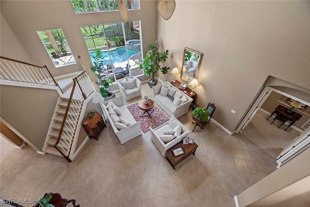 living room featuring a healthy amount of sunlight, a towering ceiling, tile patterned flooring, and stairs