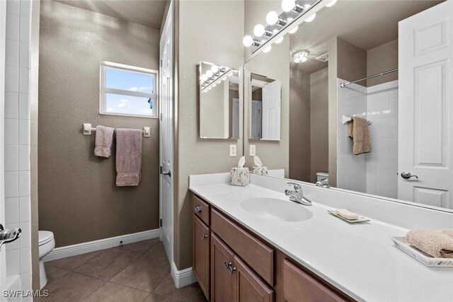 full bath featuring vanity, baseboards, tile patterned floors, walk in shower, and toilet