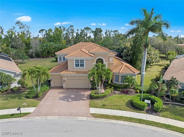 mediterranean / spanish-style home featuring a garage, a tile roof, decorative driveway, stucco siding, and a front yard