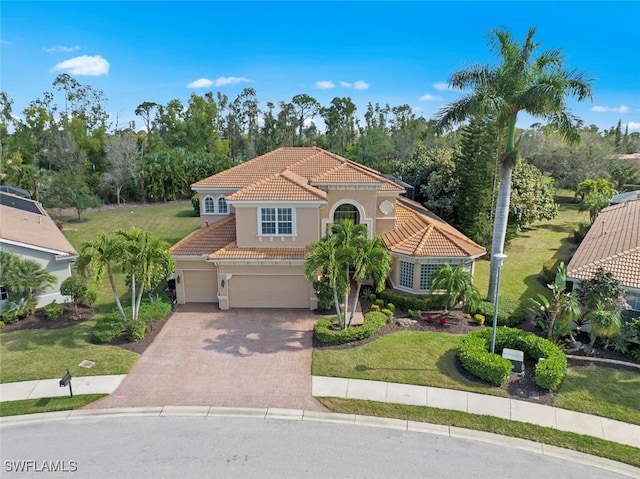mediterranean / spanish home with an attached garage, a tile roof, stucco siding, a front lawn, and driveway