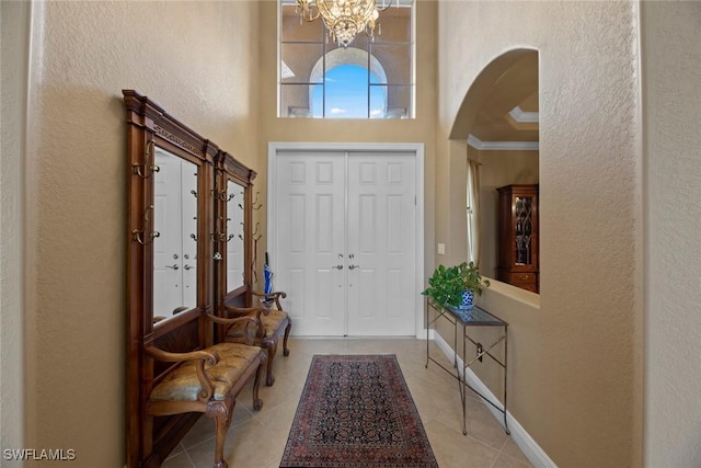 foyer entrance with arched walkways, light tile patterned flooring, a towering ceiling, and baseboards