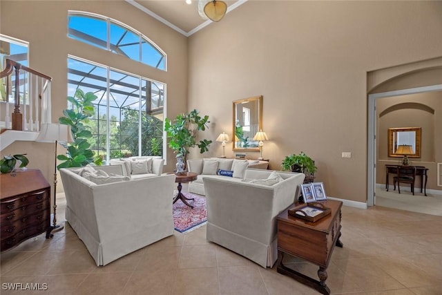 living room with light tile patterned floors, baseboards, a high ceiling, and ornamental molding