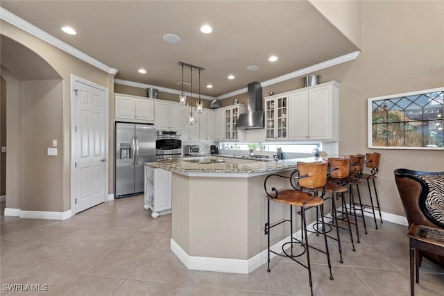 kitchen featuring arched walkways, stainless steel appliances, a peninsula, wall chimney exhaust hood, and glass insert cabinets