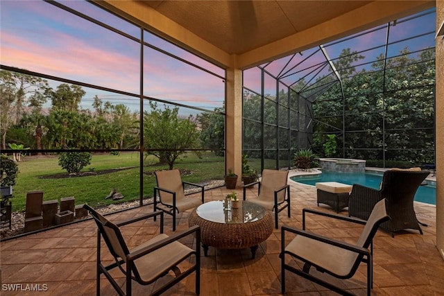 patio terrace at dusk featuring a lanai, a pool with connected hot tub, and a yard