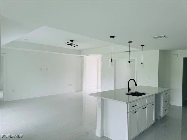 kitchen with pendant lighting, sink, a center island with sink, and white cabinets